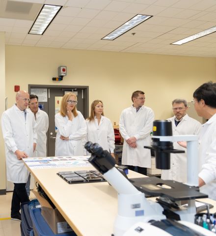 穿著白大褂的人站在實驗室的顯微鏡旁。